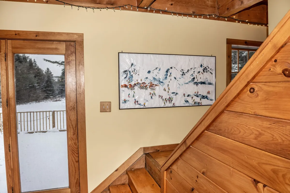 A large glass door and staircase are the focal points, with natural light filling the entryway. The door provides a clear line of sight to the outside, emphasizing easy access to nature and the surrounding reserve. Warm, inviting decor enhances the homey atmosphere.