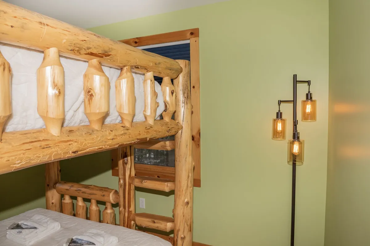 A welcoming bedroom with a modern bunk bed, green walls, and a stylish light fixture. The setup encourages relaxation and is ideal for families or groups, with a cozy, playful atmosphere and plenty of room for making memories together.