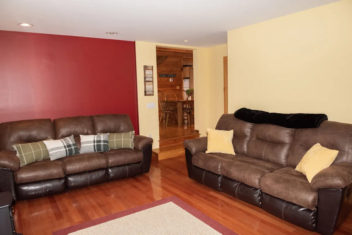 A cozy living space featuring brown leather sofas, a red accent wall, and a yellow wall, inviting socializing, relaxing, and entertaining. The arrangement encourages gatherings after a day of adventure, and the warm tones evoke a sense of comfort and togetherness.