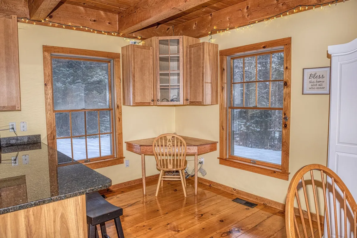 A bright, inviting kitchen area with wooden cabinets, a round table with a chair, and large windows bringing in natural light. The space is ideal for morning coffee, reading, or setting up a remote workspace while enjoying scenic views.